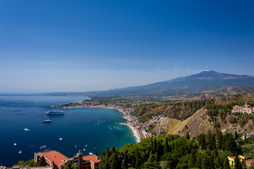 Fototapeta premium Taormina bay on a summer day with the Etna volcano in the background seen from the Greek theater of Taormina, Sicily, Italy
