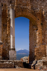 Ruins and columns of antique greek theater in Taormina and Etna Mount in the background. Sicily, Italy, Europe.