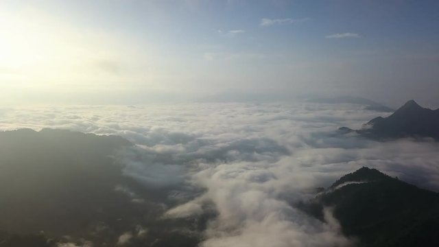 The great moment of the aerial vehicle or drone flying over the movement of great white fluffy cloud and fog around with the mountain beside. The location is taken at Phu Chi Fa, Chaingrai, Thailand.