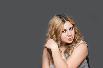 Studio shot of cool long haired young woman looking at the camera. All is on the gray background. 