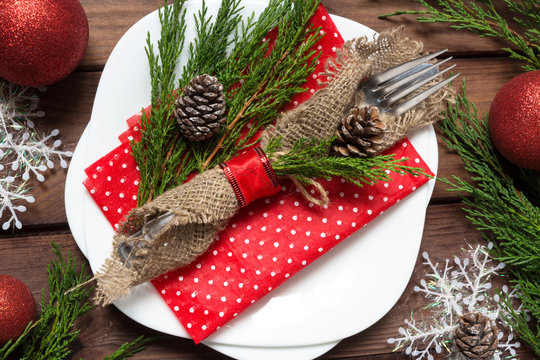 Christmas table setting with fork and knife in sackcloth and spruce branches cones and Christmas decorations on a wooden background with copy space top view flat, holiday concept