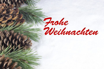 Group of pine trees and some branches with text in German "Frohe Weihnachten" in white snow background