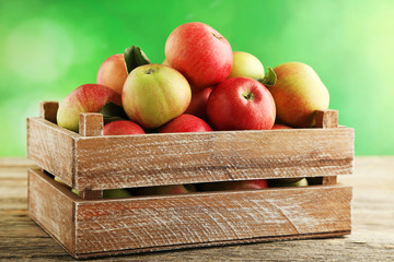 Fresh apples in basket on wooden table