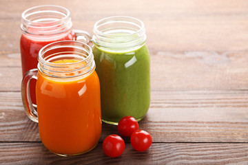 Vegetables smoothie in jars on brown wooden table