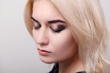 Blonde girl with bright makeup on the eyes closed and clean skin on a white isolate close-up