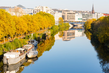 boats on river near promenade leading to city center with shopping malls and church