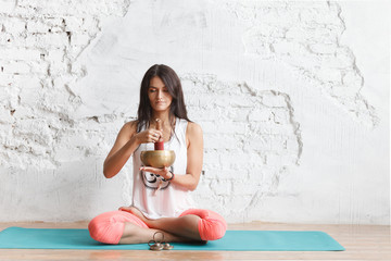 girl the yogi plays on the Tibetan singing bowl. Yoga and healthy lifestyle concept