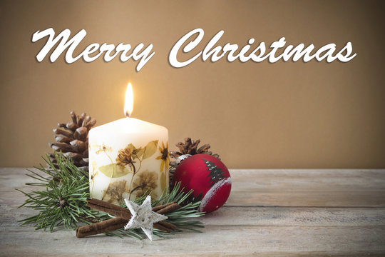 Christmas decoration with candle, pine, bauble, with text in English "Merry Christmas" in wooden background