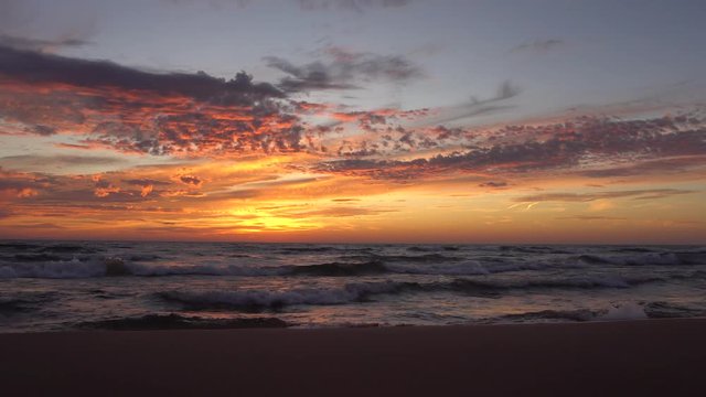 Waves washing ashore with beautiful sunset and clouds in the sky.