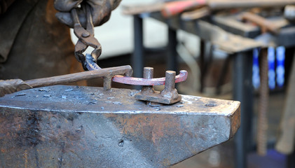 The blacksmith kicks a horseshoe