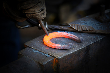 The blacksmith kicks a horseshoe