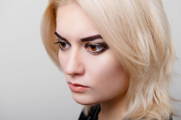 Blonde girl with bright makeup look in the direction of isolate on white closeup