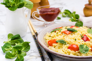 Noodles with pepper, lettuce leaves and sesame seeds in a ceramic plate