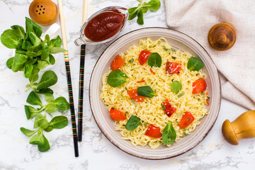 Noodles with pepper, lettuce leaves and sesame seeds in a ceramic plate. Top view