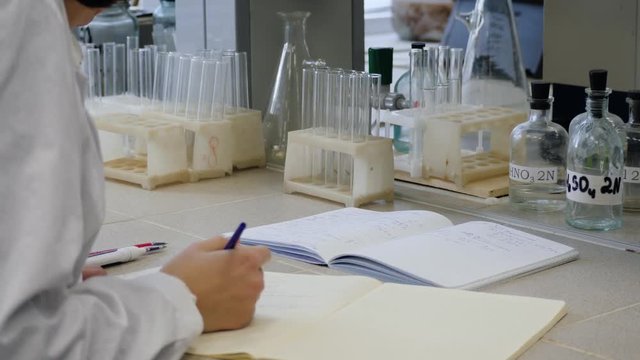 Young scientist doctor taking notes. Female scientist takes notes in the background are the tubes