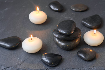 Obraz na płótnie Canvas black stones and burning candles on dark background
