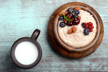 Oatmeal with berries in bowl with milk top view