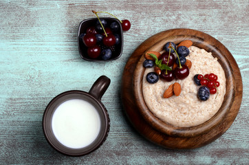 Oatmeal with berries in bowl with milk top view