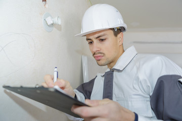 male engineer writing on clipboard at construction site