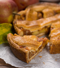 Traditional homemade apple pie with nuts and cinnamon close up and fresh ripe Golden Reinette apples