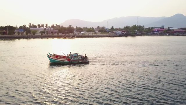 Aerial shot of fishing boast on the Prek Kampong river in Kampot, Cambodia with Bokor National Park in the distance at sunset.