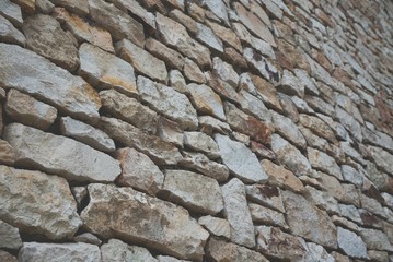 Stone wall background of colorful stones with matt film effect. Perspective view. Selective focus