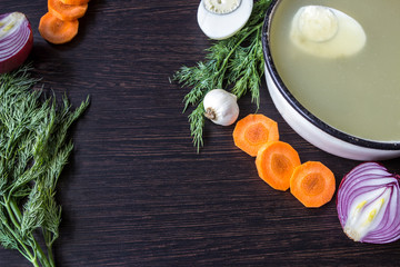 Soup with sorrel, vegetables and boiled egg, red onion, carrots, garlic, dill on dark wooden table