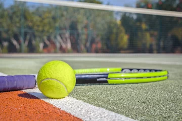 Zelfklevend Fotobehang macro tennis ball and racket on hard court. blurry net in the background © Myst