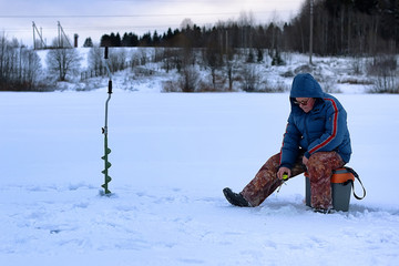 Fototapeta na wymiar elderly man fishing in the winter on the lake