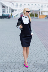 Business lady woman dressed in working serious skirt and shirt posing on street with note book blond hairs and pink high heels sexy