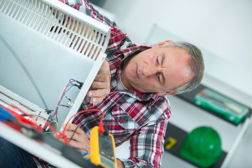 man using an electronic measuring device for fixing the heater