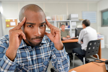 Man sat at desk holding head