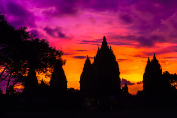Silhouette of a temple complex against the background of a fiery red orange purple sky after...