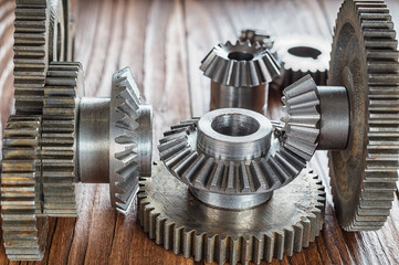 Steel gear and reducer, engineering details on wooden background. Metal cogwheels. Industry Concept.