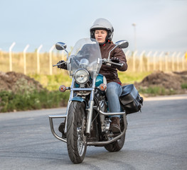 Fototapeta na wymiar Woman motorcyclist riding solo on chopper on asphalt urban road