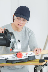Fototapeta na wymiar young adult female woodworker cutting board in workshop