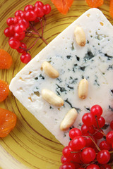 Cheese with mold, fruits and nuts on a dark blue background, cinnamon, buckwheat, red berries, pop art, minimalism, cheese with honey for Christmas, cheese on a plate for a vegan
