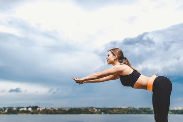 Cute sporty girl showing stretching exercises outdoor