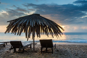 Sun loungers with umbrella on the beach, sunrise