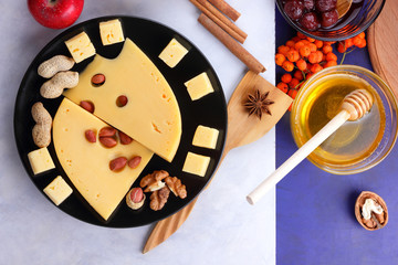 Cheese with mold, fruit, hard cheese with holes on a dark blue background, cheese on a black plate, fruits, nuts, honey, jam, Christmas dinner