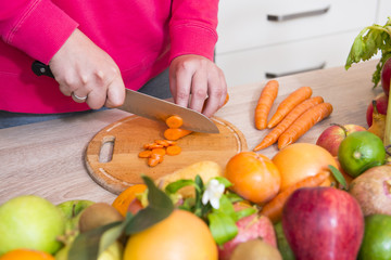 Obraz na płótnie Canvas Cutting carrot on kitchen table