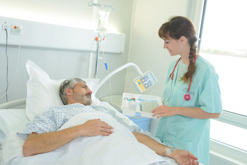 Fototapeta premium male patient lying in a hospital bed while nurse checking