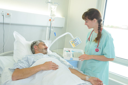 male patient lying in a hospital bed while nurse checking