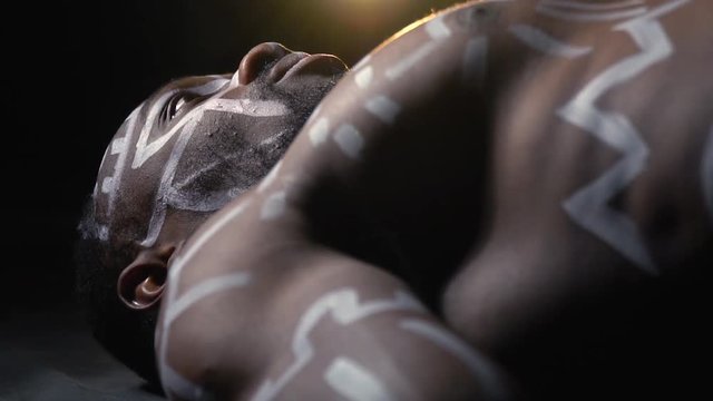Papuan with a beard and white patterns on the body resurrected after death, slow motion