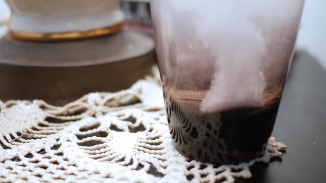 Dissolving medical tablet drops into water glass on bedstand ALT