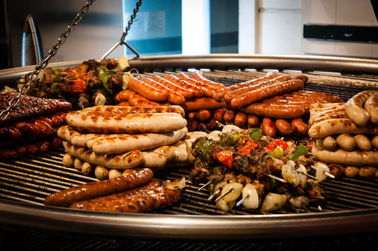 Assortment of grilled sausages and kebabs on big hanging grill at Christmas market in Paris (France).
