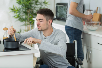 disabled young man in wheelchair cooking in the kitchen