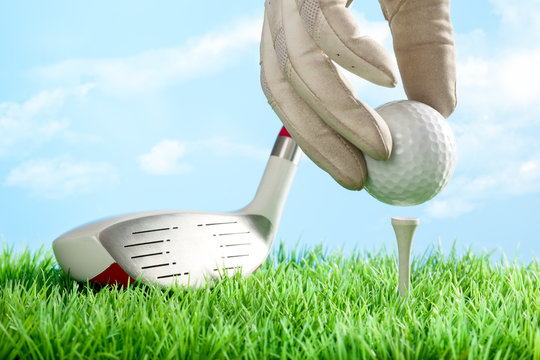Series of golfing equipment concept pictures..Shot in studio on grass with blue background: Teeing the Ball