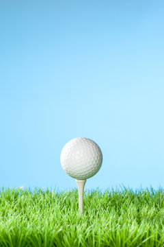 Series of golfing equipment concept pictures..Shot in studio on grass with blue background: Ball on Tee with Copy Space