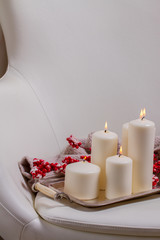 White burning advent candles with red berries and knitted blanket on chair
